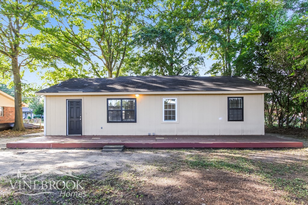 a small white house with a porch and some trees